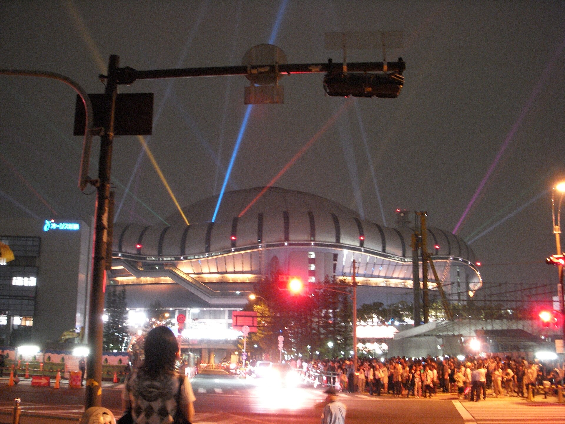 Kyocera Dome Osaka lit up at night with searchlights and crowds outside, the venue for the 2026 MAMA Awards