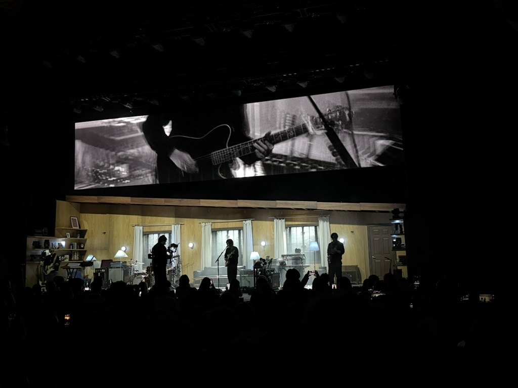 Black-and-white footage on the screen above the stage